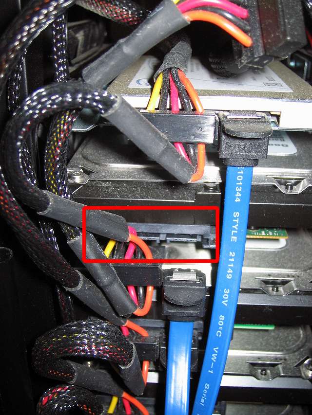 破損した 3.5 インチ HDD プラスチックドライブレール交換のため、HDD に取り付けてある SATA 電源ケーブルと SATA ケーブルを取り外し